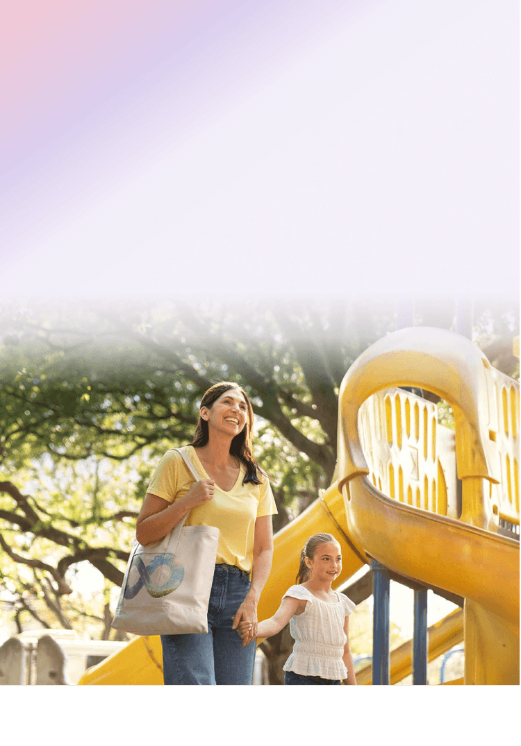A woman and her daughter walking together at a playground