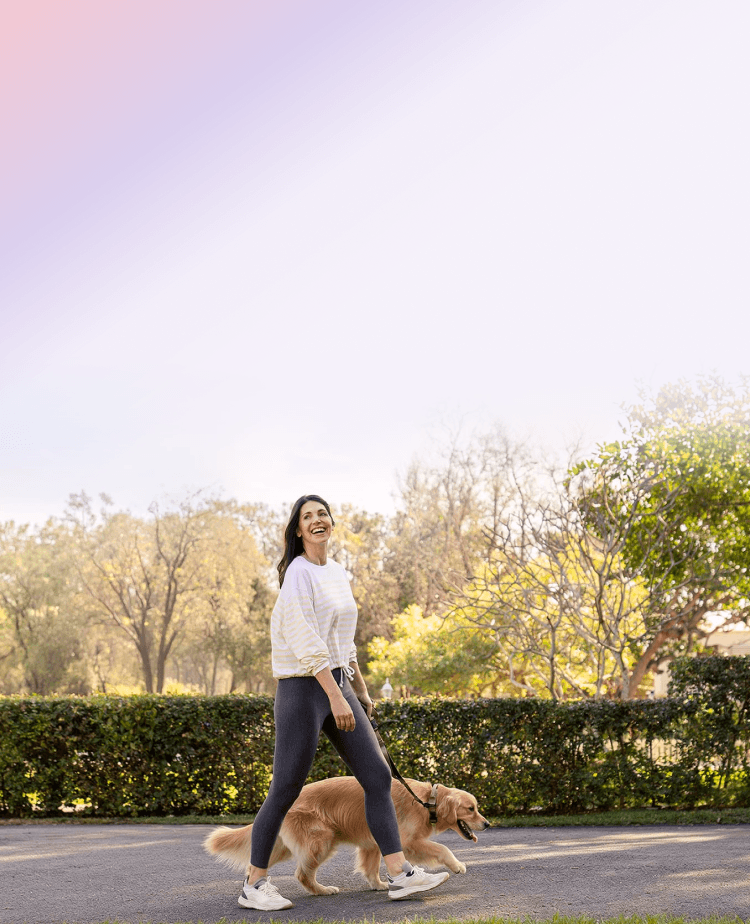 A woman walking her golden retriever in a park