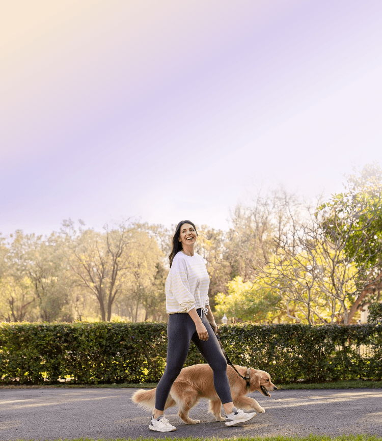 A woman walking her dog in a park on a sunny day