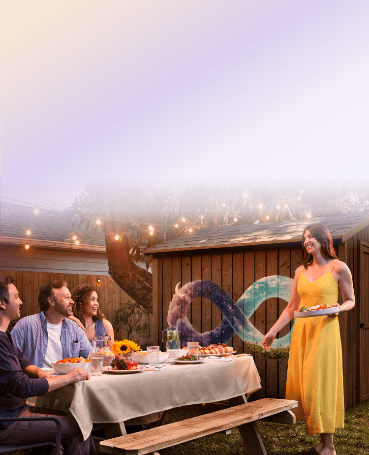 People enjoying an outdoor dinner party with an infinity symbol mural in the background