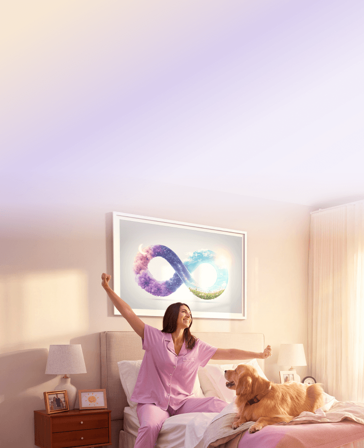 A woman stretching in bed with her dog, with an infinity symbol wall art above
