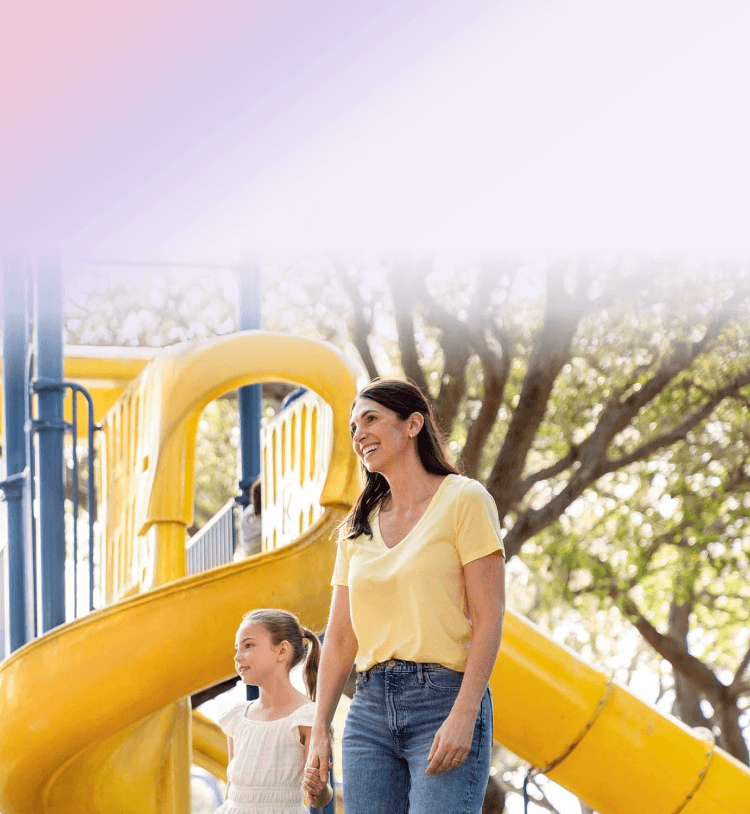 A woman and her daughter walking together at a playground