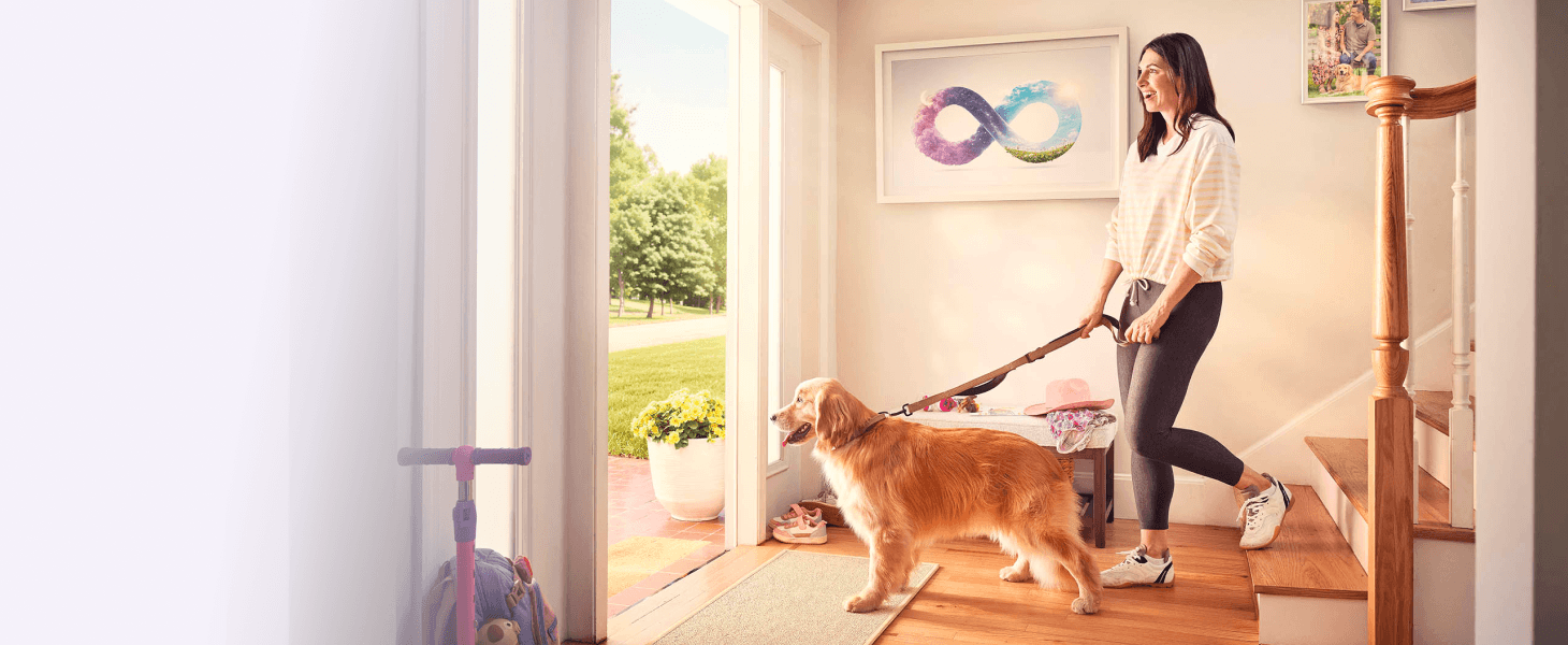A woman walking her dog out the front door with an infinity symbol painting on the wall