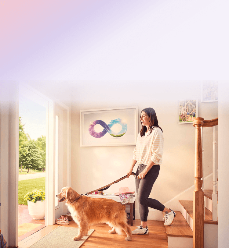 A woman walking her dog out the front door with an infinity symbol painting on the wall